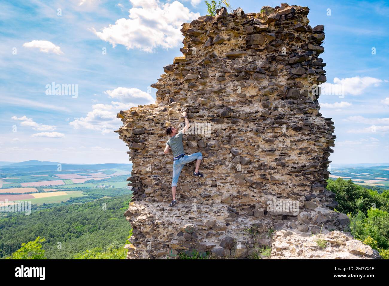 Ein Mann klettert die Überreste einer Burgmauer hoch, Szanda, Ungarn Stockfoto