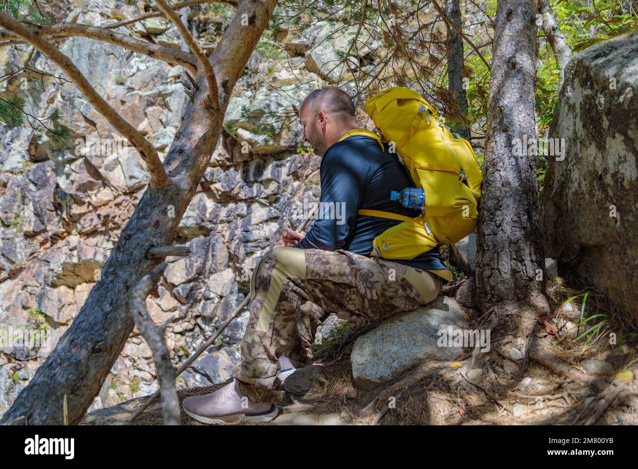 Ein männlicher Tourist mit Rucksack setzte sich auf eine Wanderung in die Berge. Stockfoto