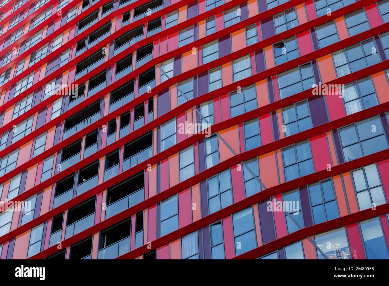 Hintergrund der Außenfassade des modernen Gebäudes mit Details von roten und weißen Aluminiumpaneelen und schwarzem dunklen reflektierten Glas auf horizontalen Fenstern. Stockfoto