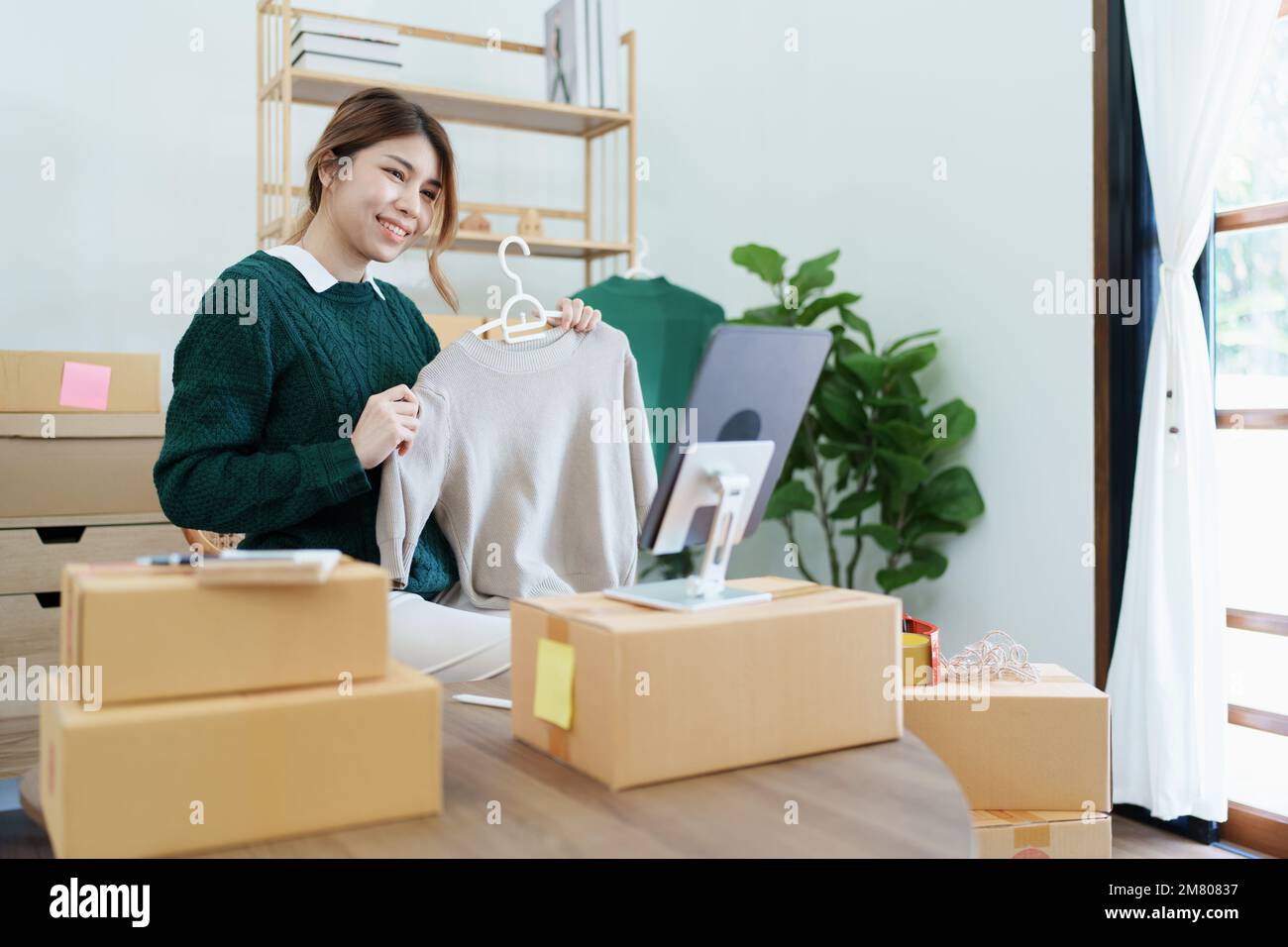 Gründung eines kleinen Unternehmertums einer unabhängigen jungen asiatischen Frau im Internet, die einem Kunden bereits Produkte auf einem Tablet vorstellte Stockfoto