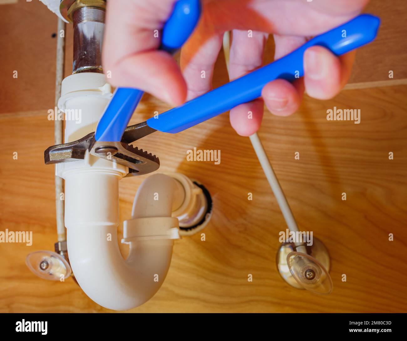 Nahaufnahme des Klempners mit einem verstellbaren Schraubenschlüssel zur Reparatur der Leckage im Abflussrohr des Waschbeckens. Stockfoto