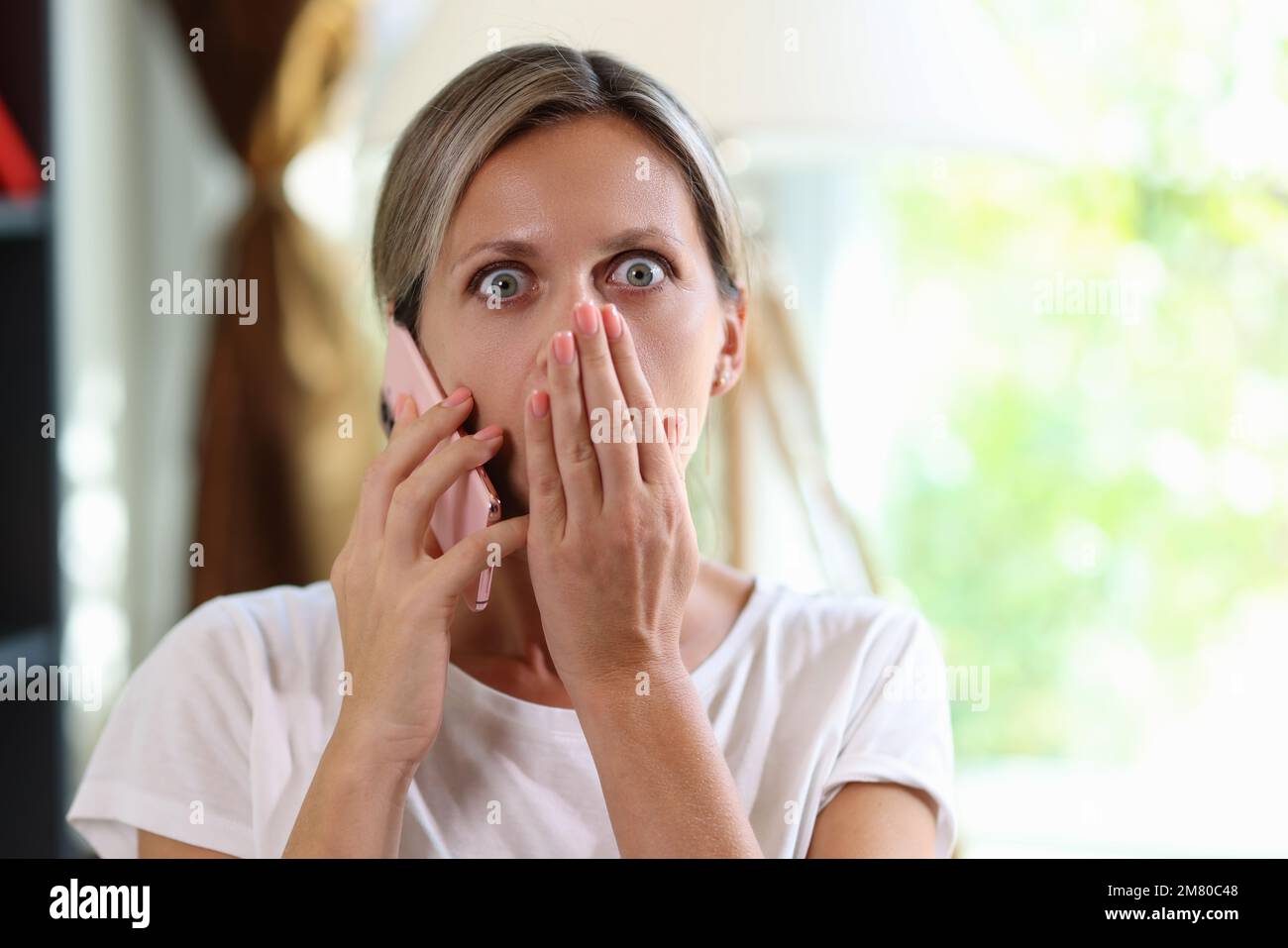Gestresste und schockierte Frau, die mit dem Smartphone spricht und in die Kamera schaut. Stockfoto
