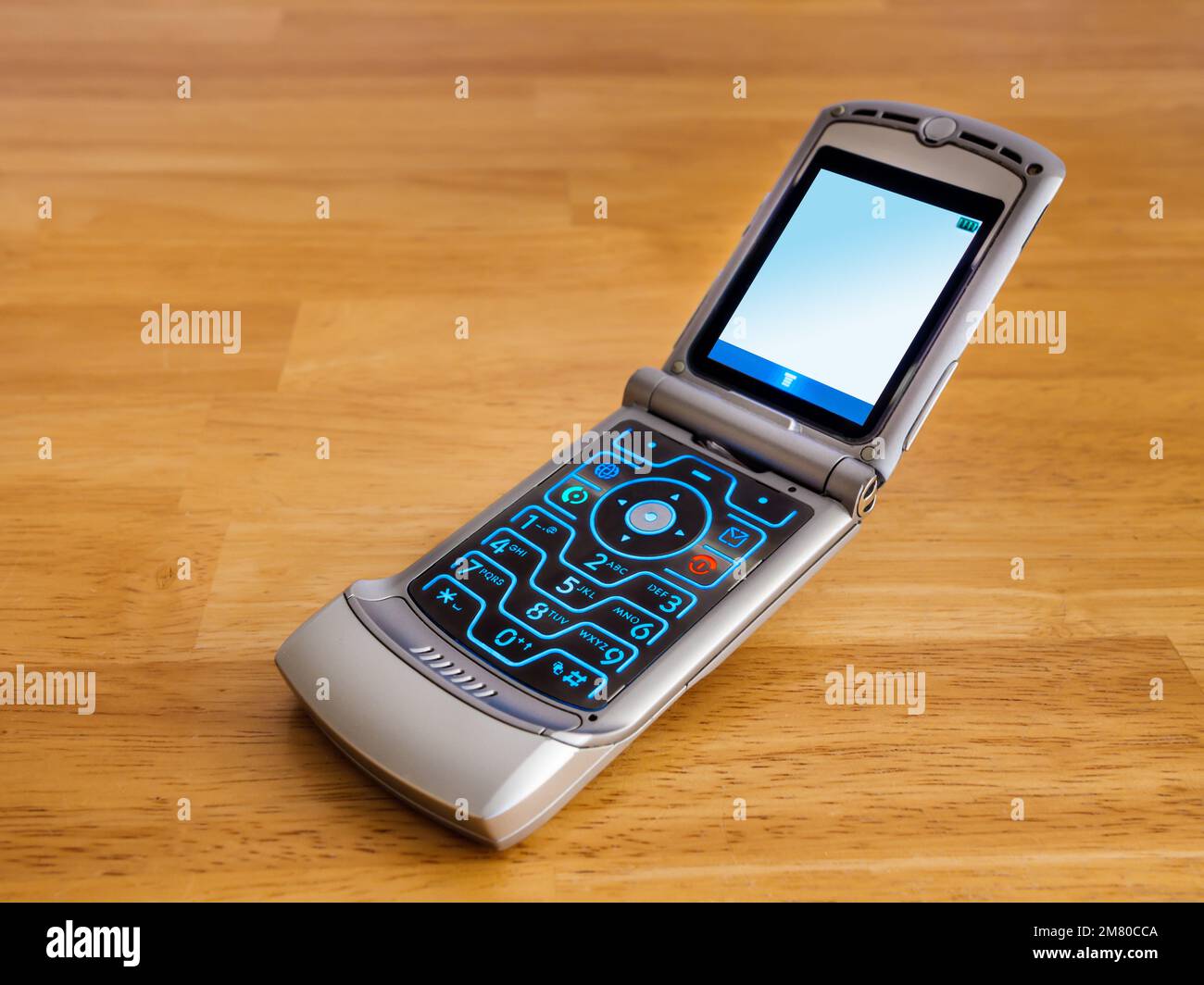 Retro-Klapphandy. Altmodisches Mobiltelefon mit Drucktaste auf Holzschreibtisch. Stockfoto