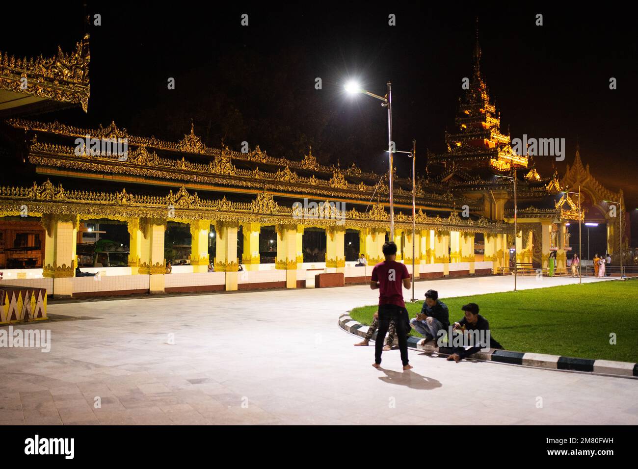 Tägliches Leben Myanmar - Menschen bei Nacht in der Nähe eines goldenen Tempels im Dorf Dawei. Dawei, Stockfoto