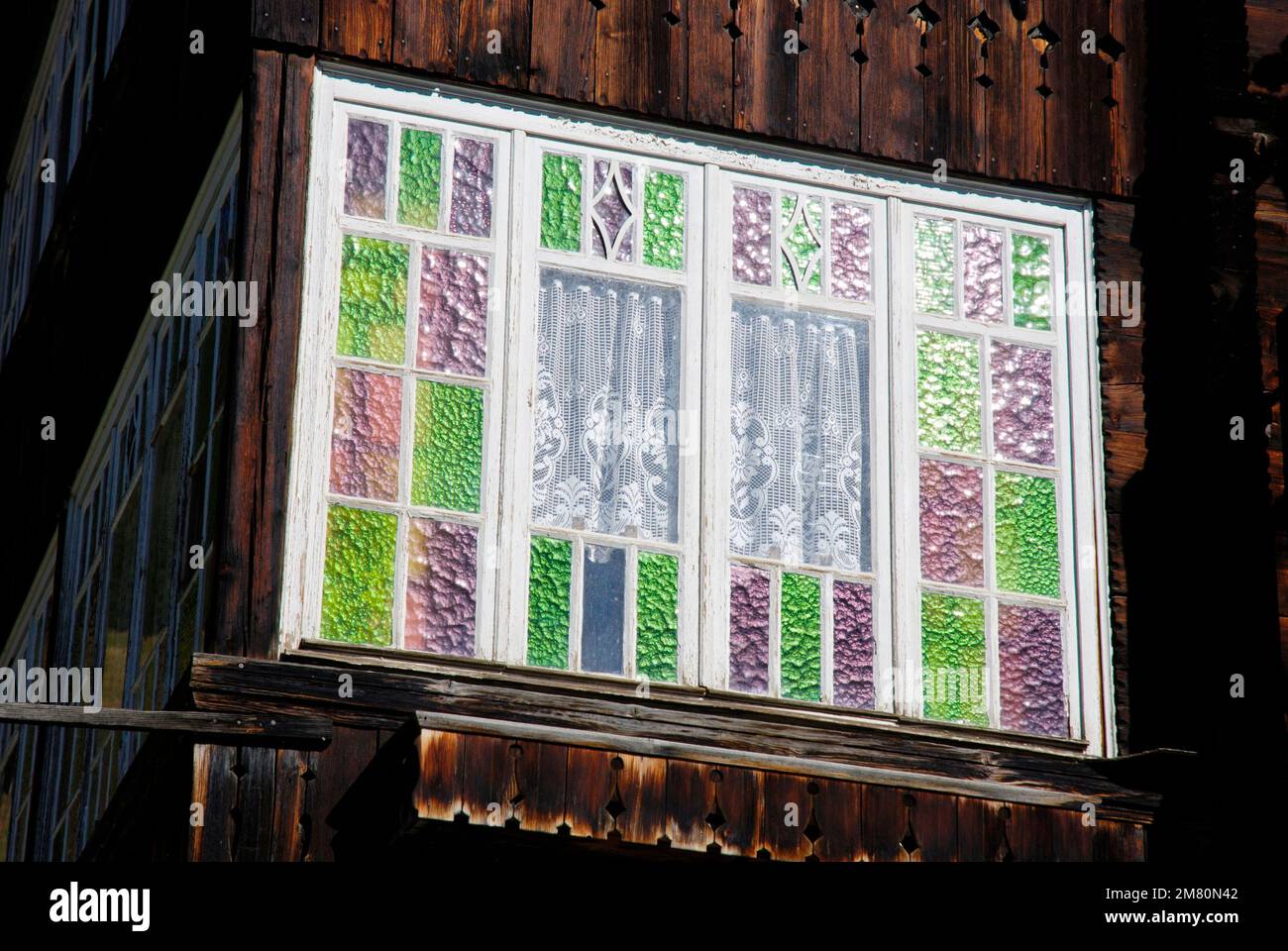 Buntes Gitterfenster, Fensterglas in einem alten Holzhaus Stockfoto