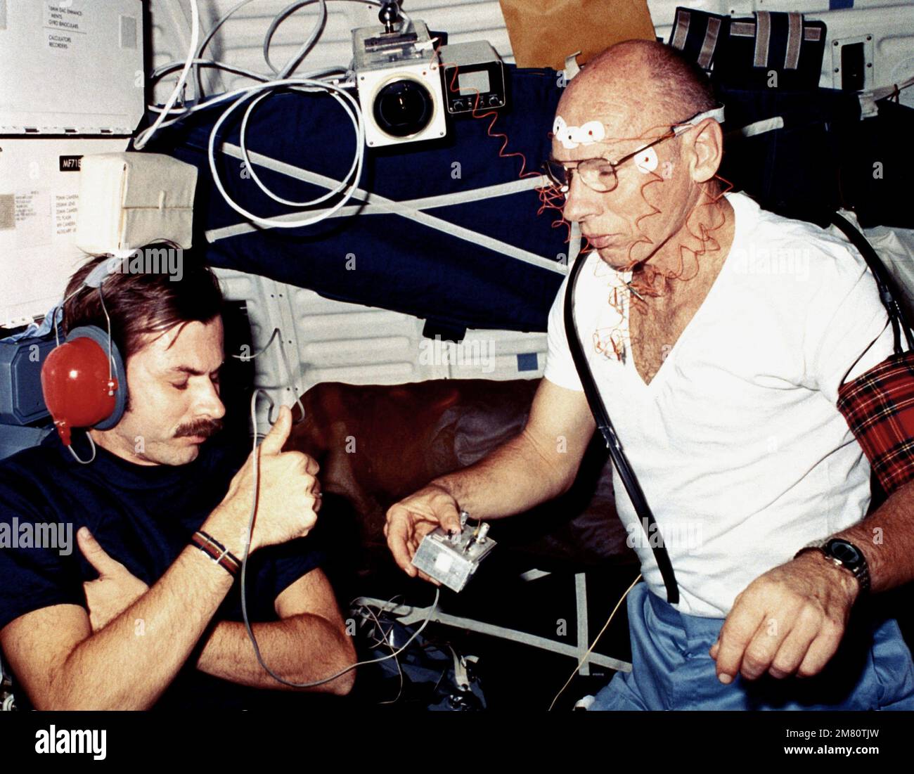 Dr. William E. Thornton, Missionsspezialist, führt einen Audiometrietest an Dale A. Gardner, Missionsspezialist, im Mitteldeckbereich des umkreisten Space Shuttle Orbiter Challenger (STS-8) durch. Land: Unbekannt Stockfoto