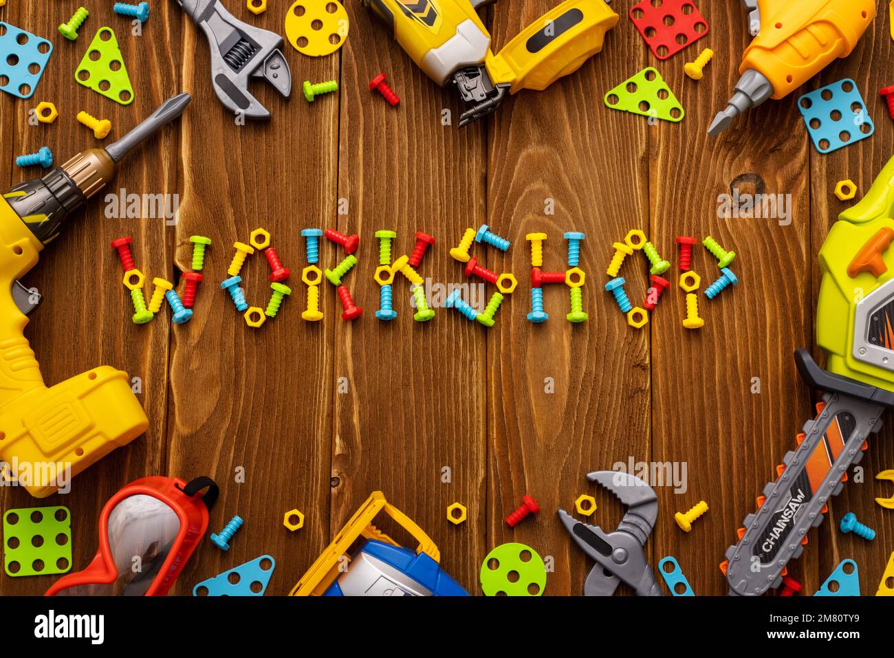 Spielzeugwerkzeuge, Bolzen und Muttern mit TEXTWERKSTATT auf Holzhintergrund Stockfoto