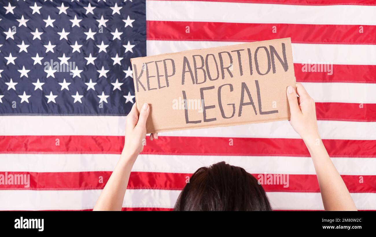 Frau hält einen leeren Karton mit dem Space for Text-Zeichen US-Flagge auf dem Hintergrund. Protest gegen Abtreibungsverbot. Frauenstreik. Frauenrechte f Stockfoto