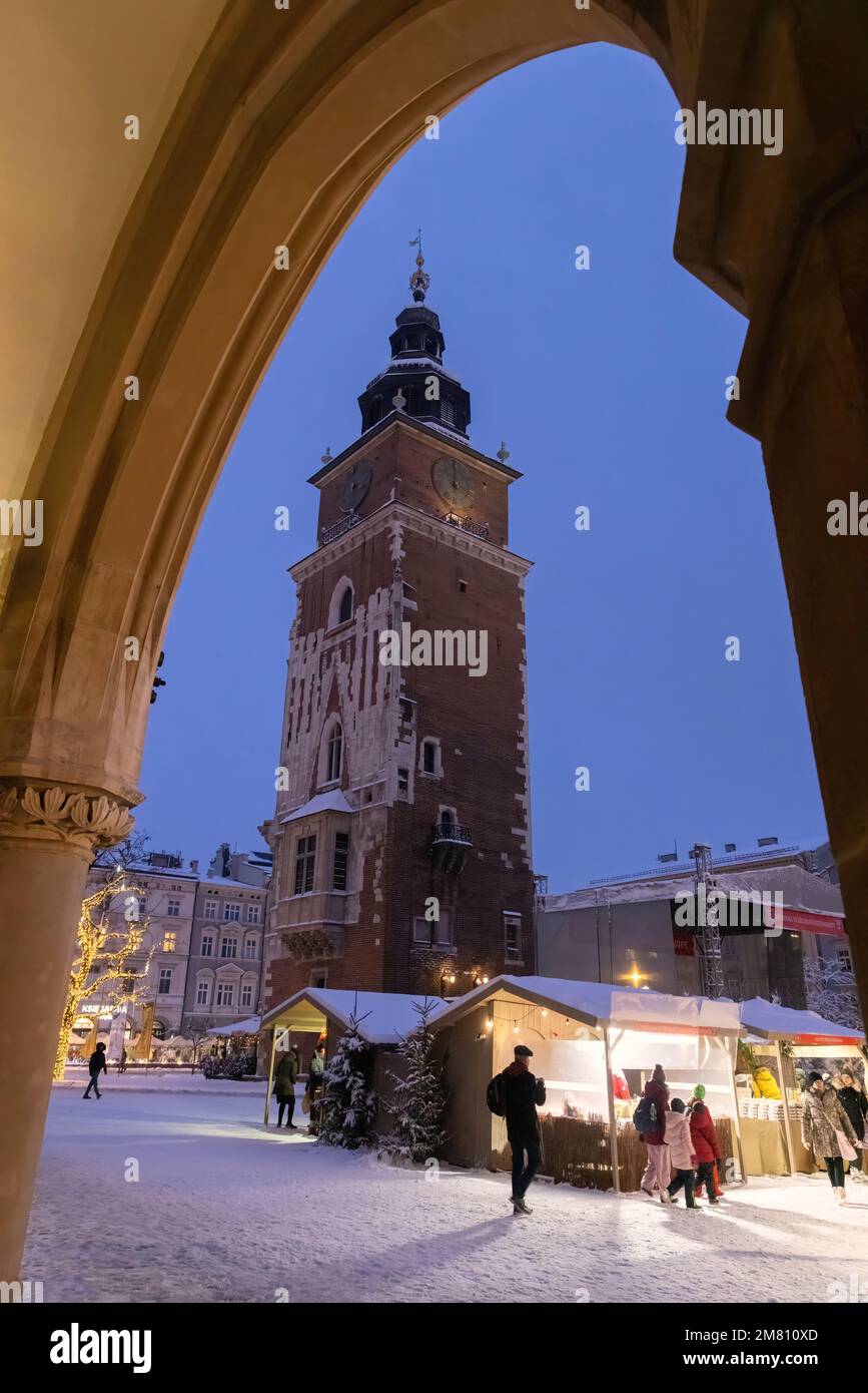 Szene unter einem Bogen der mittelalterlichen Textilhalle des Krakauer Weihnachtsmarkts und des Rathausturms bei Nacht, Krakauer Altstadt, Krakau Polen Stockfoto