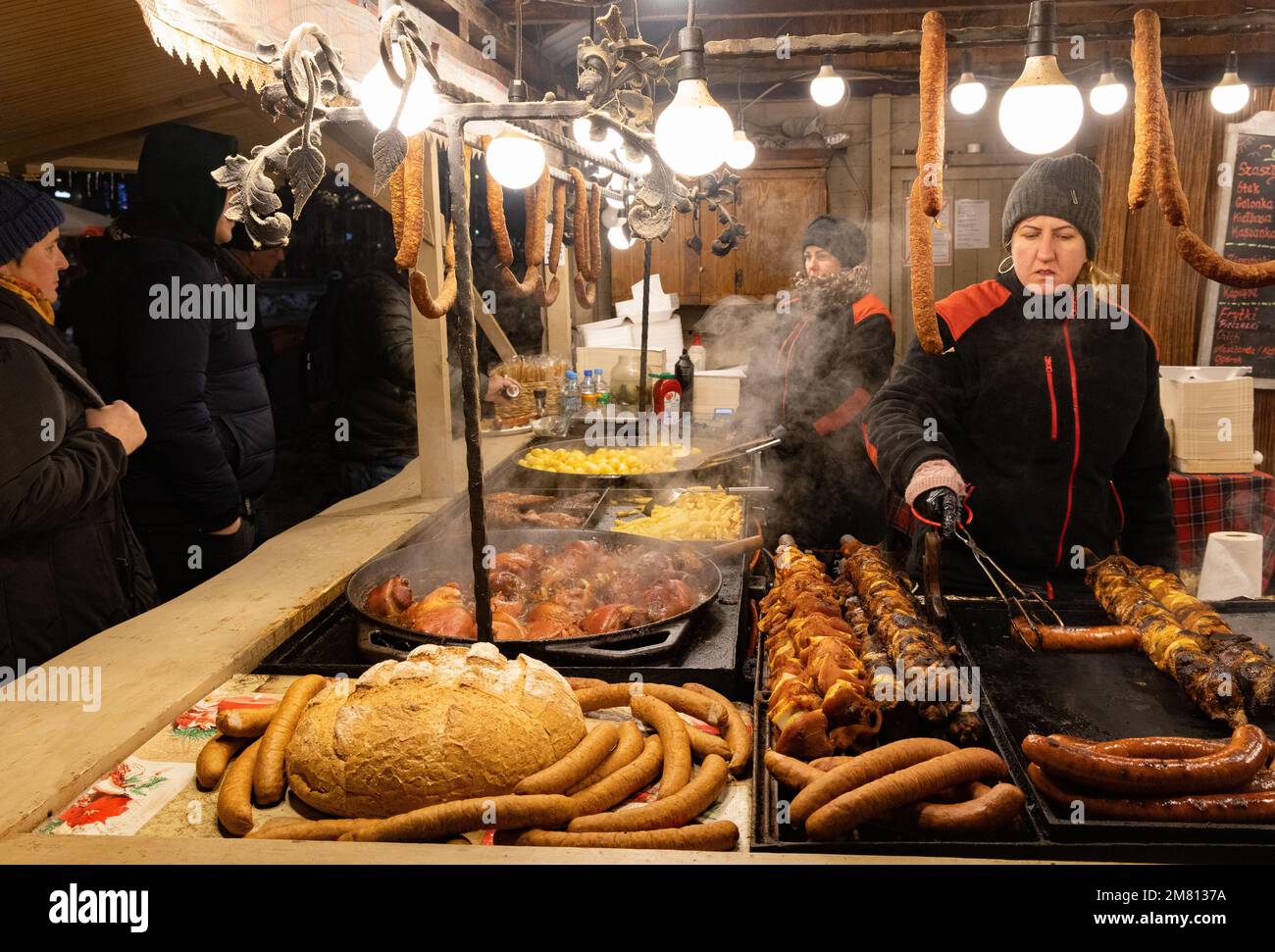 Krakauer Weihnachtsmarkt Krakau Polen – Fleisch wird nachts an einem Imbissstand auf dem Hauptmarktplatz, in der Krakauer Altstadt, Polen, Europa zubereitet Stockfoto