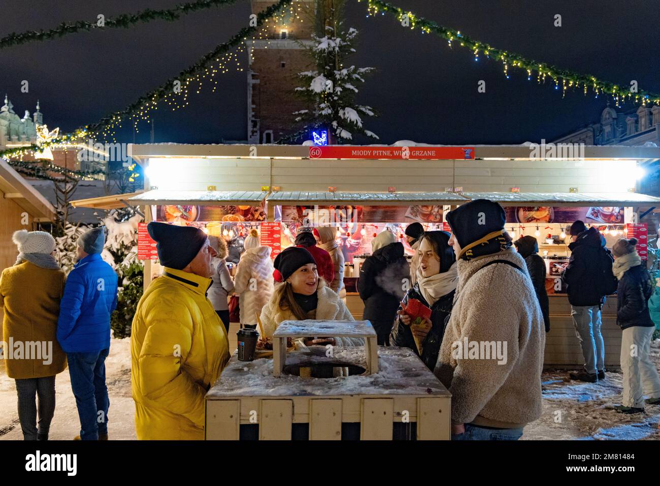 Krakauer Weihnachtsmarkt - Leute, die sich unterhalten, trinken und Spaß haben in der Nacht, Krakauer Hauptmarktplatz, Krakau, Polen Europa Stockfoto