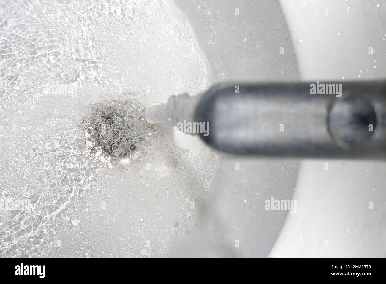 Wasser fließt aus dem Wasserhahn über der Ablauföffnung in der Wanne Stockfoto
