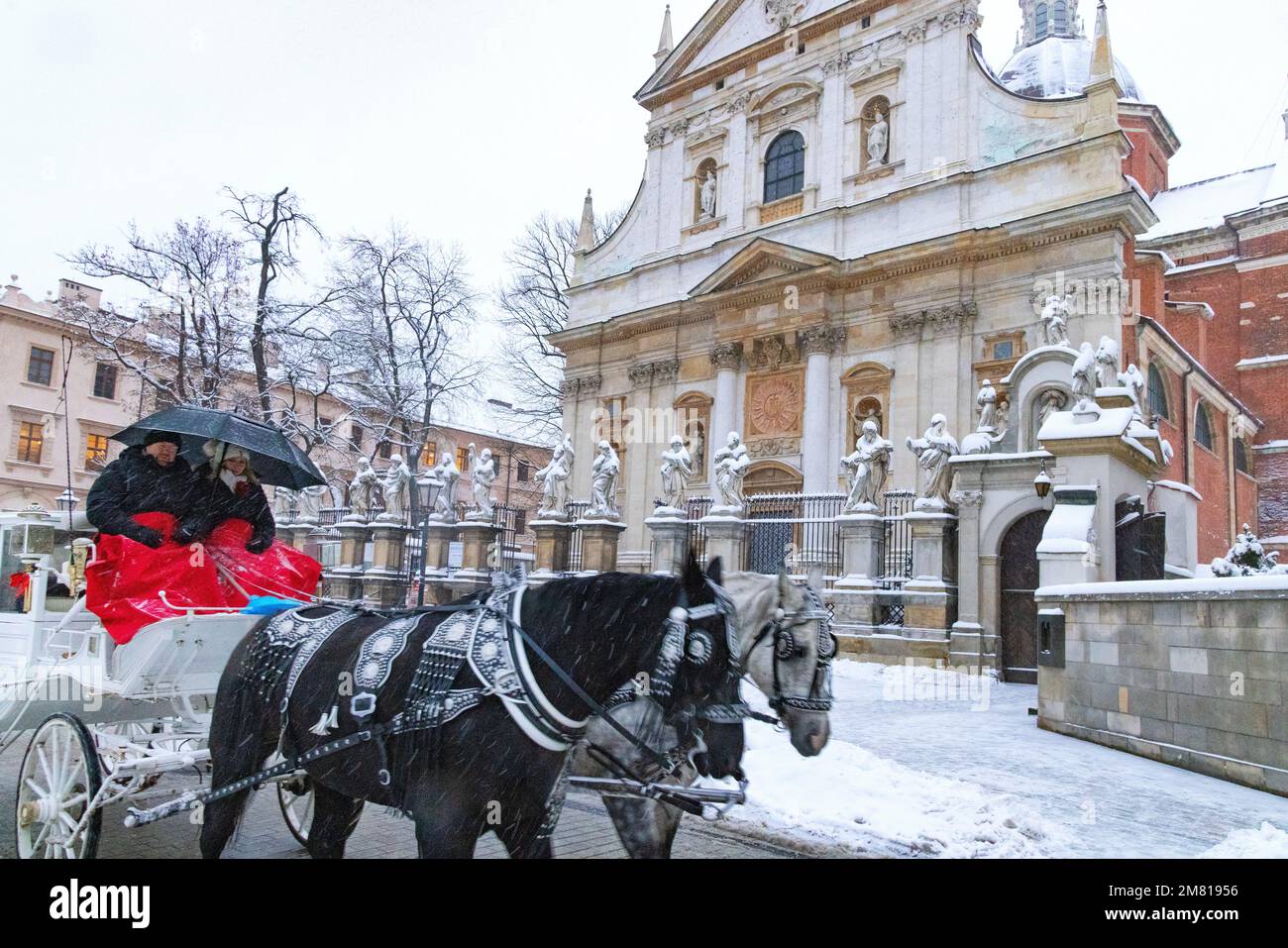Krakauer Tourismus - ein Pferd und eine Kutsche passieren die Kirche der Heiligen Peter und Paul im Winterschnee, Krakau Polen Europa Stockfoto