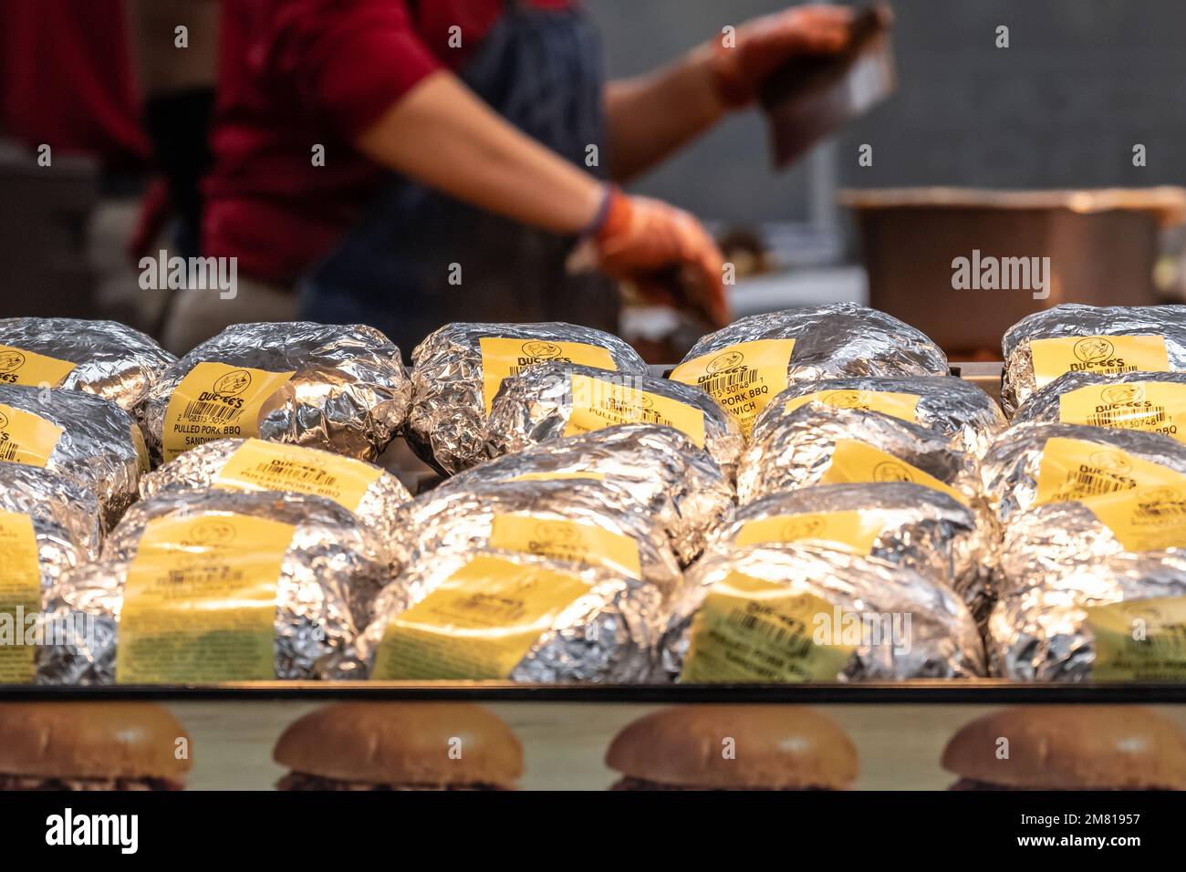 Buc-ee's Angestellter hackt Fleisch hinter einem Wärmestablett voller gegrillter Sandwiches bei Buc-ee's in Warner Robins, Georgia. (USA) Stockfoto