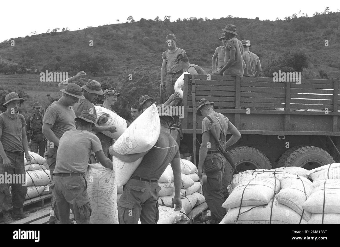 Soldaten laden während der AHUAS TARA II (BIG PINE)-Operation eine Ladung Mais für das Welternährungsprogramm mit einem C-130 Hercules-Flugzeug auf Lastwagen. Die US-Agentur für internationale Entwicklung sponsert das Programm. Betreff Betrieb/Serie: AHUAS TARA II (GROSSE KIEFER) Basis: Aguacate Country: Honduras (HND) Stockfoto