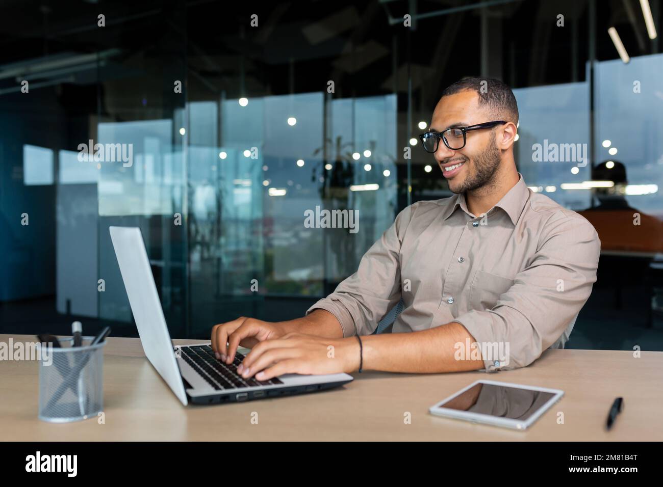 Junger erfolgreicher indischer Programmierer, der in einem modernen Entwicklungsunternehmen arbeitet, der mit dem Laptop Code für Software schreibt. Stockfoto