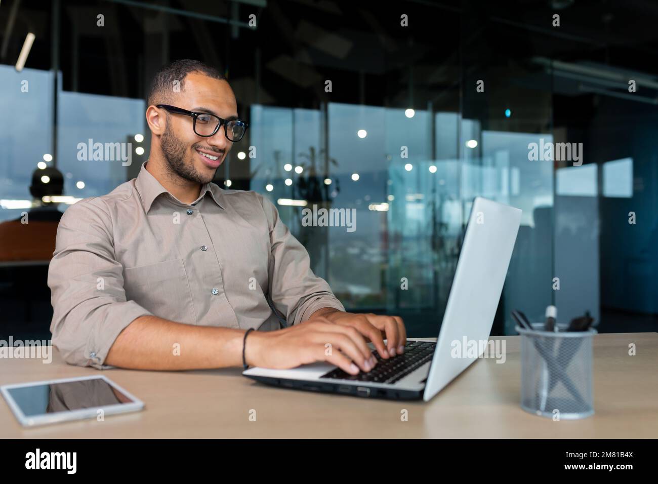 Junger erfolgreicher indischer Programmierer, der in einem modernen Entwicklungsunternehmen arbeitet, der mit dem Laptop Code für Software schreibt. Stockfoto