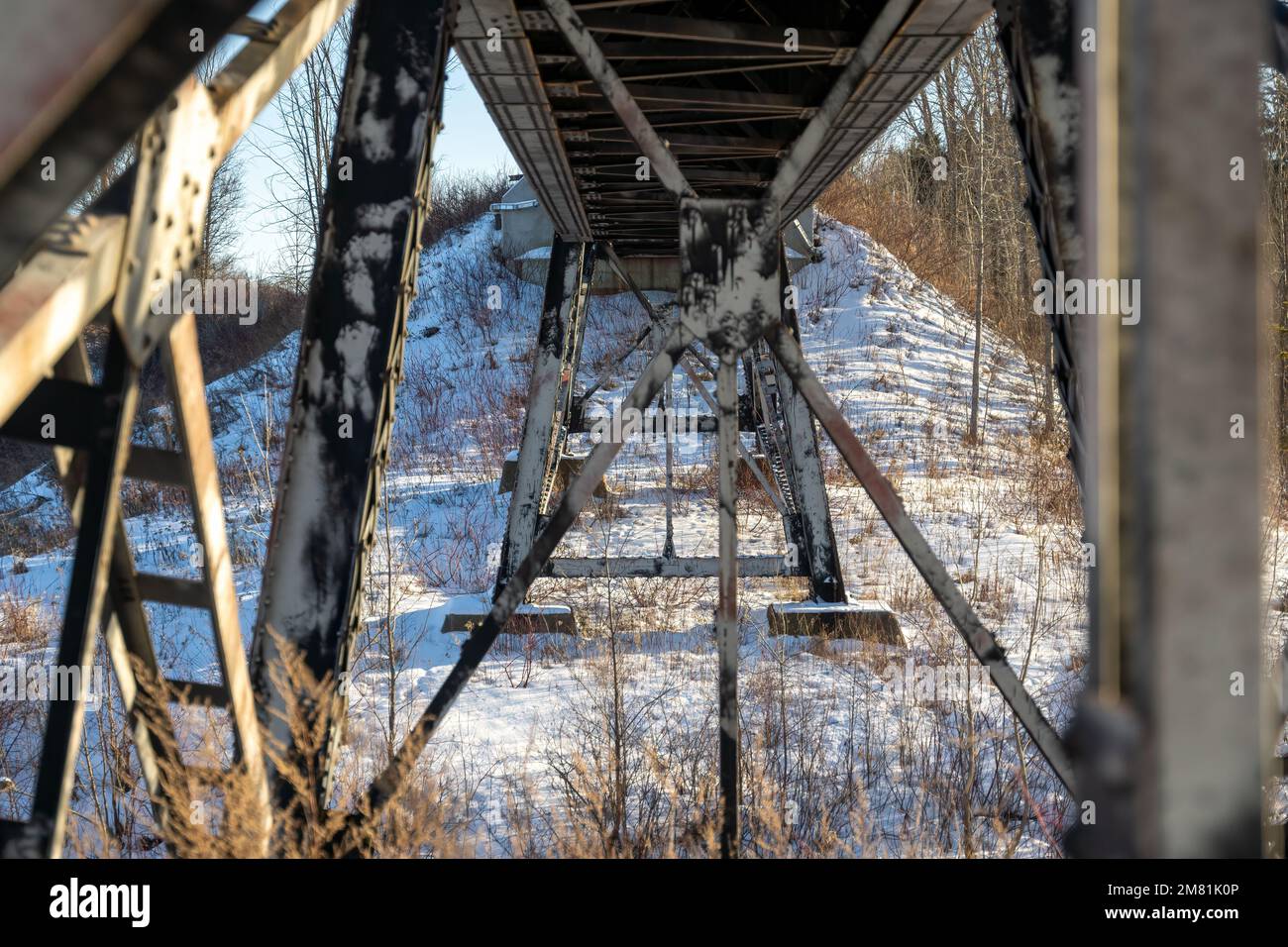 Stahlbalken unter einer Eisenbahnbrücke an einem sonnigen Winternachmittag in Nord-Ontario. Stockfoto