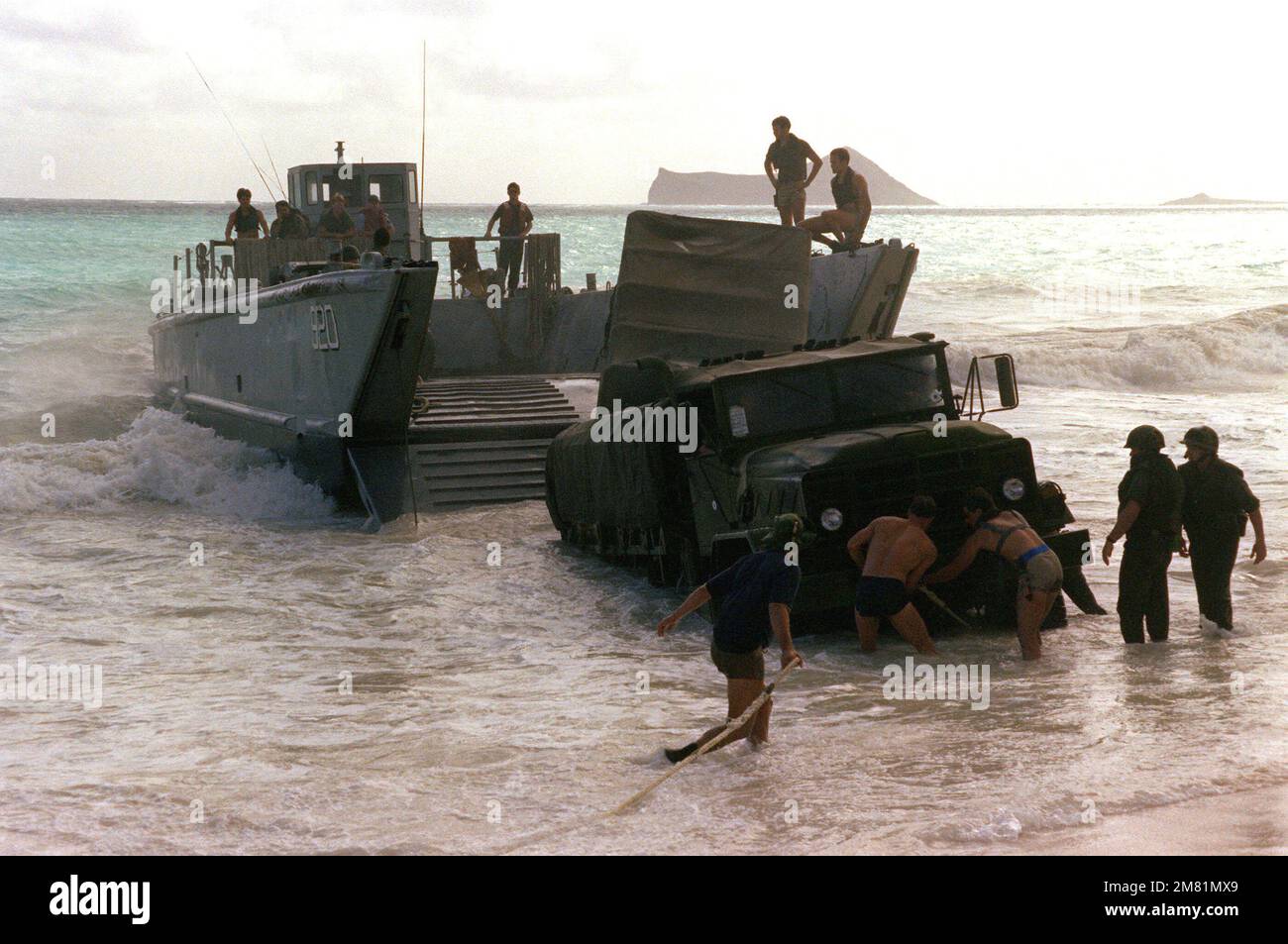 Marines befestigen Abschleppseile an einem 2 1/2-Tonnen-Lkw, der nach dem Beladen von einem mechanisierten Landefahrzeug (LCM Mark 8) während des Betriebs KERNAL BLITZ im Sand feststeckte. Betreff Betrieb/Serie: KERNAL BLITZ Base: Bellows Beach, Oahu Bundesstaat: Hawaii (HI) Land: Vereinigte Staaten von Amerika (USA) Stockfoto