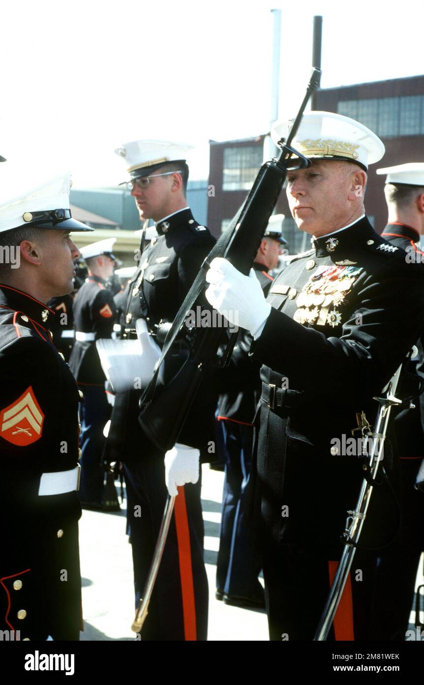 General Paul X. Kelley, Befehlshaber des Marine Corps, inspiziert ein Gewehr, während er eine Ehrenwache des Marine Corps während der Zeremonie für die von Oliver Hazard Perry geleitete Raketenfregatte USS NICHOLAS (FFG 47) in der Werft Bath Iron Works überprüft. Basis: Bath Bundesstaat: Maine (ME) Land: Vereinigte Staaten von Amerika (USA) Stockfoto