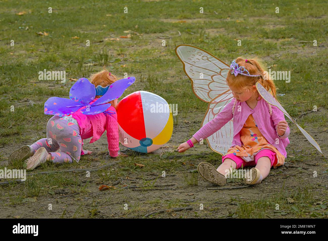 Kleine Kinder mit Schmetterlingsflügelkostümen, die auf dem Gras spielen Stockfoto