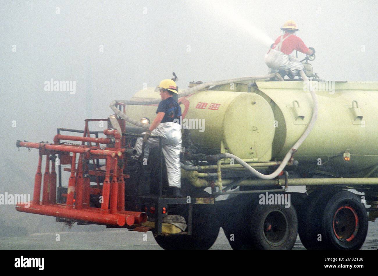 Ein Feuerwehrauto der 3. Civil Engineering Feuerwehr ist mit amerikanischen und philippinischen Feuerwehrleuten besetzt, die versuchen, das Feuer zu löschen, das die USA umschlingt Anlage 3., Vorratsgeschwader, überdachter Lagerbereich 11A. Der Schaden wurde auf $3 Millionen Dollar geschätzt. Stützpunkt: Clark Air Base Staat: Luzon Country: Philippinen (PHL) Stockfoto