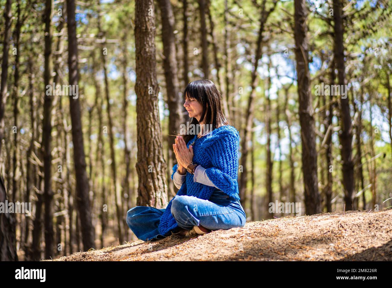 Seitenansicht einer Frau, die sich im Wald die Hände zusammenschlägt. Namaste-Pose. Stockfoto