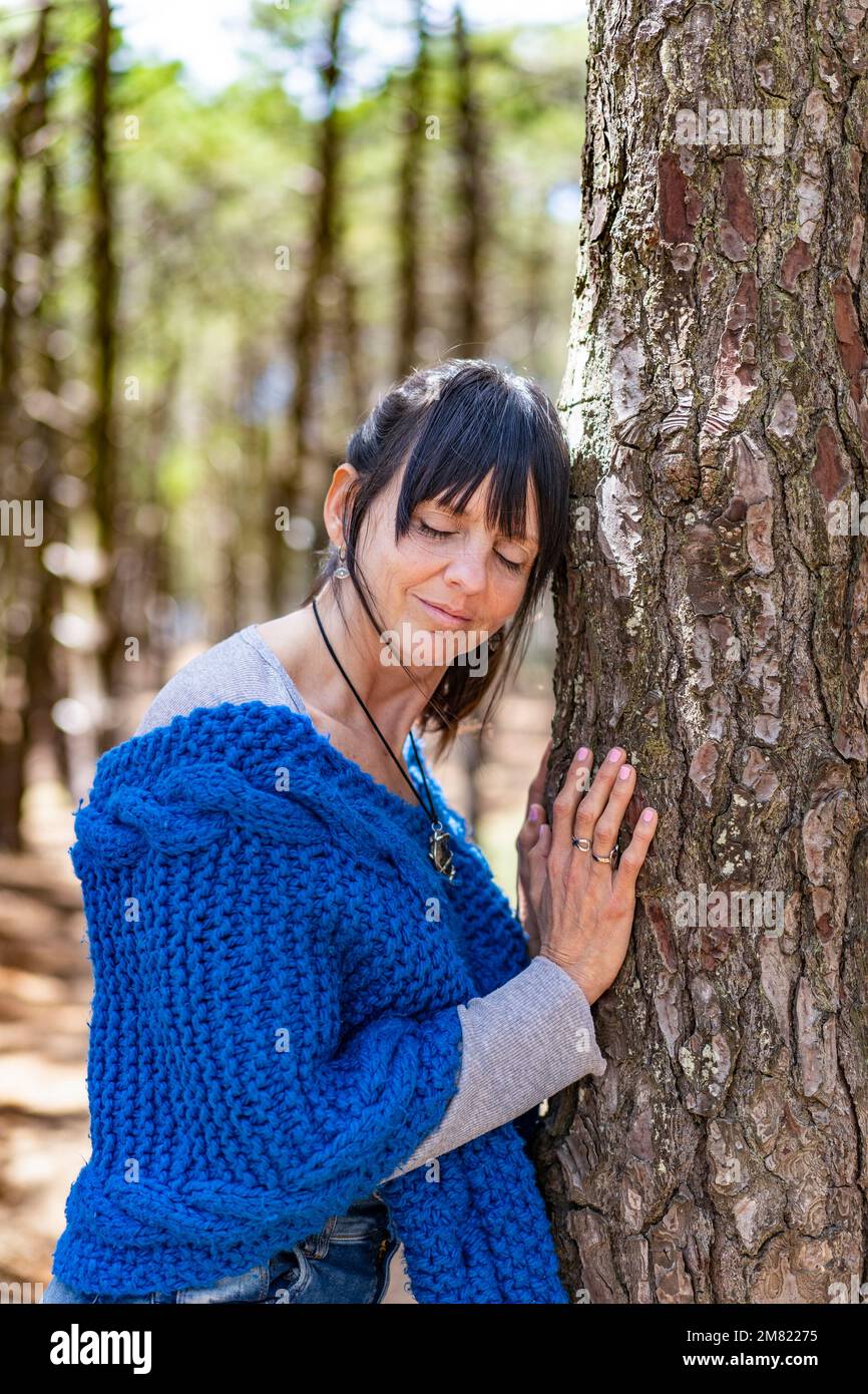 Eine Umweltschützerin umarmt einen Baum im Wald. Stockfoto