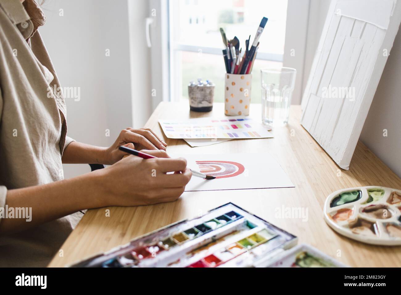 Frau malt zu Hause mit Aquarellfarbe Stockfoto