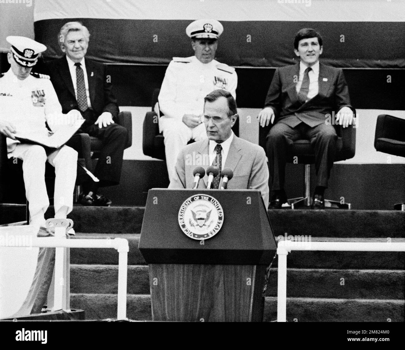 Vizepräsident George H. Bush spricht während der Zeremonie für das Schlachtschiff USS IOWA (BB 61). Hinter ihm sitzen von rechts nach links: Der Sekretär der Marine John F. Lehman Jr., Admiral Wesley McDonald, Oberbefehlshaber der US-Atlantikflotte, und Captain Gneckow, Befehlshabender Offizier. Das IST das dritte Mal, dass die IOWA in Betrieb genommen wird. Basis: Pascagoula Bundesstaat: Mississippi (MS) Land: Vereinigte Staaten von Amerika (USA) Stockfoto