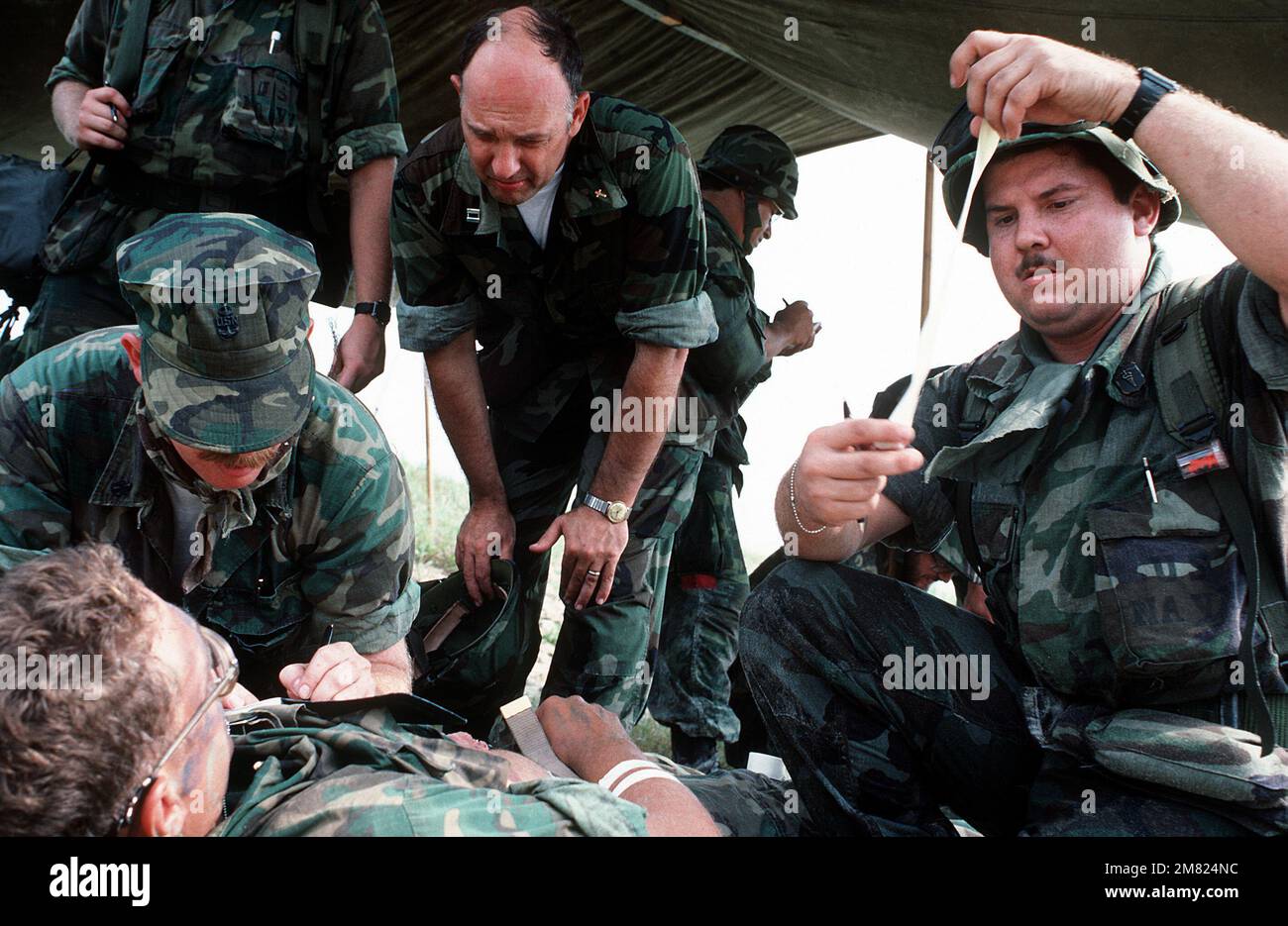 Marine Reserve Sanitäter des 4. Medizinischen Bataillons helfen einem simulierten Verletzten, während ein Navy Kaplan ihn während einer gemeinsamen Navy/Marine Amphibien Brigade Trainingsübung tröstet. Basis: Marinestützpunkt, Camp Lejeune Bundesstaat: North Carolina (NC) Land: Vereinigte Staaten von Amerika (USA) Stockfoto