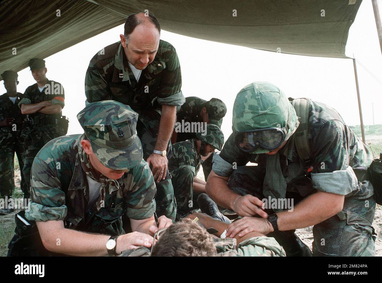 Marine Reserve Sanitäter des 4. Medizinischen Bataillons helfen einem simulierten Verletzten, während ein Navy Kaplan ihn während einer gemeinsamen Navy/Marine Amphibien Brigade Trainingsübung tröstet. Basis: Marinestützpunkt, Camp Lejeune Bundesstaat: North Carolina (NC) Land: Vereinigte Staaten von Amerika (USA) Stockfoto