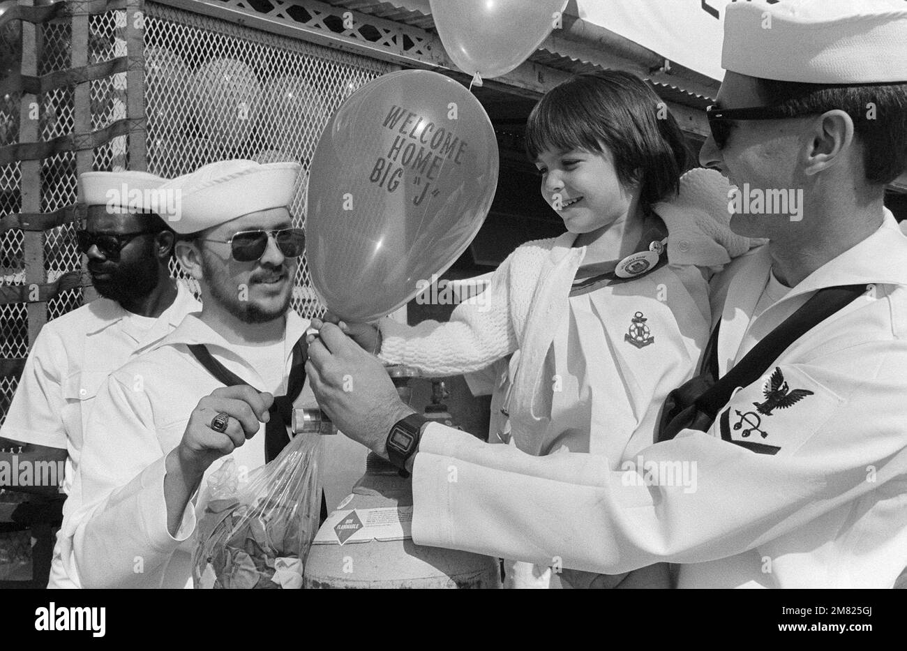 Sonar Technician 3. Class (ST3) Robert Johnson gibt dem dreijährigen Kirsten Coons während der Homecoming des Schlachtschiff USS NEW JERSEY (BB 62) einen „Welcome Home Big J“-Ballon. Kirstens Vater, ein Crewmitglied AUS NEW JERSEY, kehrt nach 11 Monaten auf See zum Heimathafen zurück. Basis: Marineflugstation, Long Beach Bundesstaat: Kalifornien (CA) Land: Vereinigte Staaten von Amerika (USA) Stockfoto