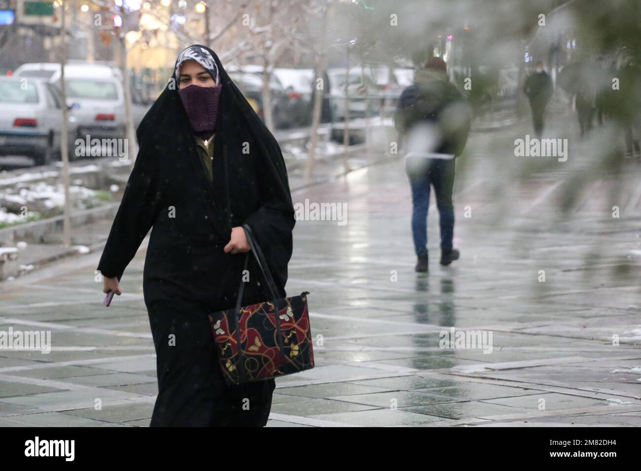 Teheran, Teheran, Iran. 11. Januar 2023. Eine verschleierte iranische Frau in einem schwarzen Chador läuft am 11. Januar 2023 inmitten des Schnees in Teheran, Iran. (Kreditbild: © RouzbritFouladi/ZUMA Press Wire) NUR REDAKTIONELLE VERWENDUNG! Nicht für den kommerziellen GEBRAUCH! Stockfoto