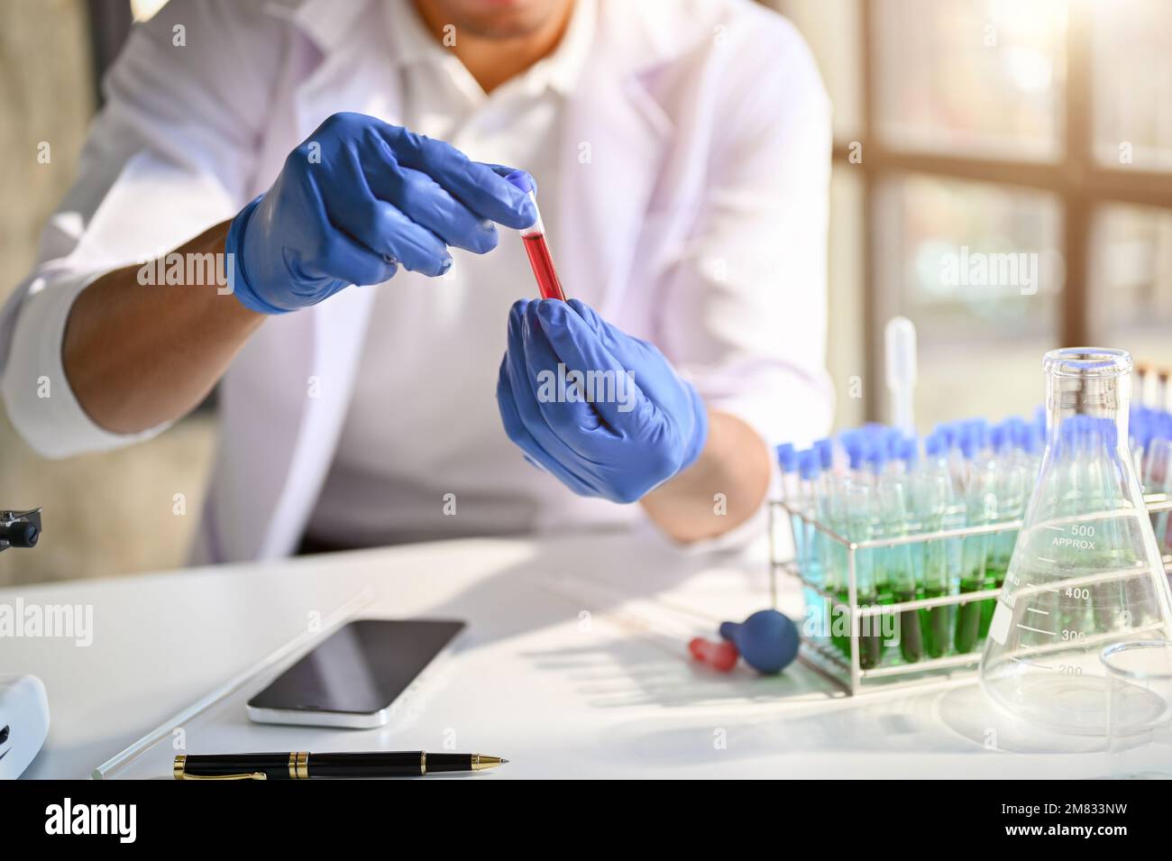 Professioneller männlicher Wissenschaftler oder Chemiker, der im forensischen Labor arbeitet, testet neue Serumproben. Freigestellte Aufnahme Stockfoto