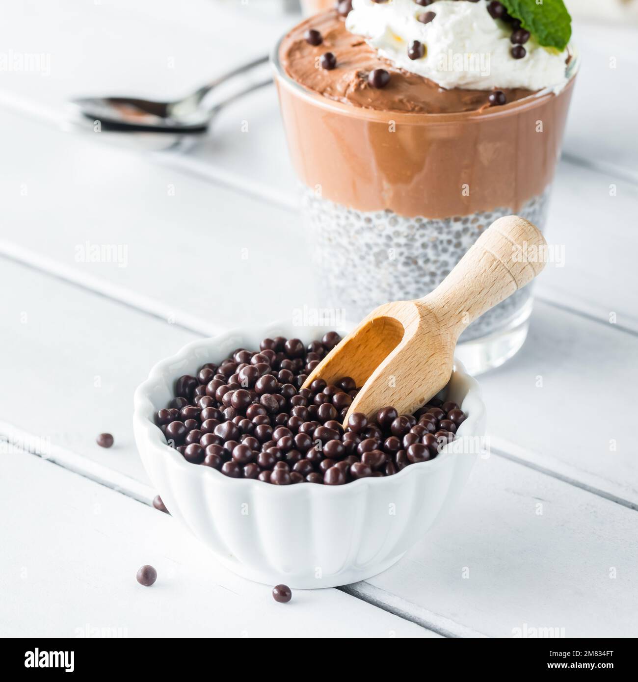Mit Schokolade überzogene Quinoa-Puffs in einer kleinen Schüssel mit einem Holzlöffel. Stockfoto