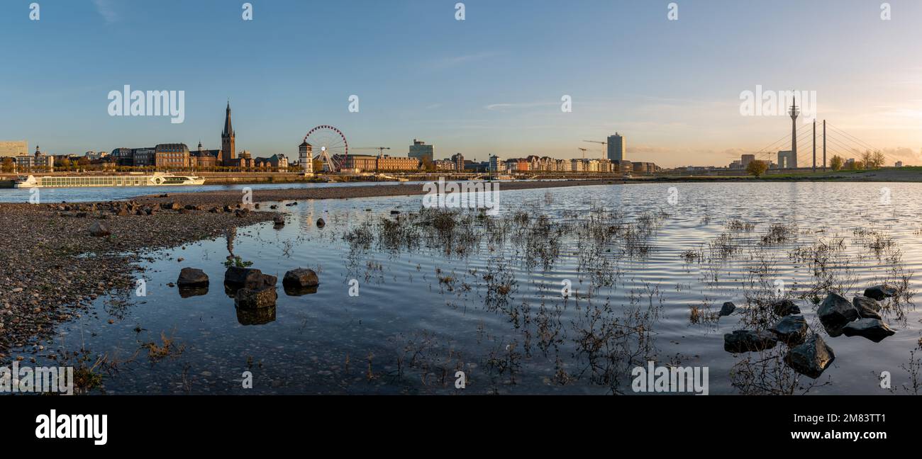 DÜSSELDORF, DEUTSCHLAND - 24. NOVEMBER 2022: Sonnenuntergang am Rhein mit dem Stadtbild Düsseldorf im Hintergrund am 24. November 2022 in Deutschland Stockfoto