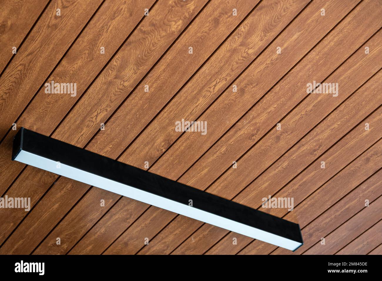 PVC-Deckenplatte mit holzartiger Vinylverkleidung und moderner Beleuchtung Stockfoto