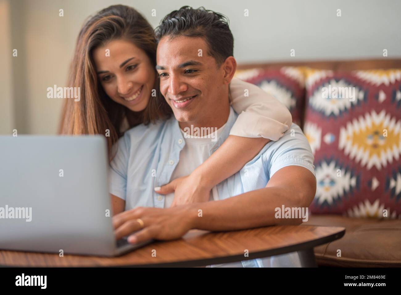 Fröhliches gemischtes Millennial-Paar, das zu Hause Zeit mit einem Laptop verbringt, Happy Young interrassistische Liebhaber, die auf dem Boden mit Computer sitzen, arbeiten oder einkaufen Stockfoto