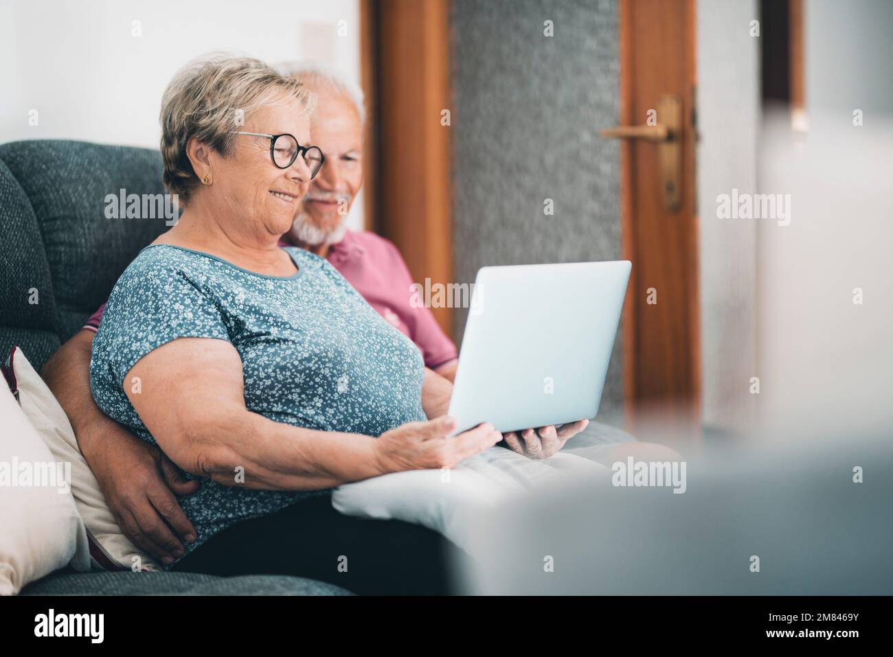 Seniorenpaar zu Hause, das sich mit einem Laptop entspannen kann. Neuer moderner Lebensstil für ältere Rentner. Mann und Frau mit Computer und Internetanschluss Stockfoto