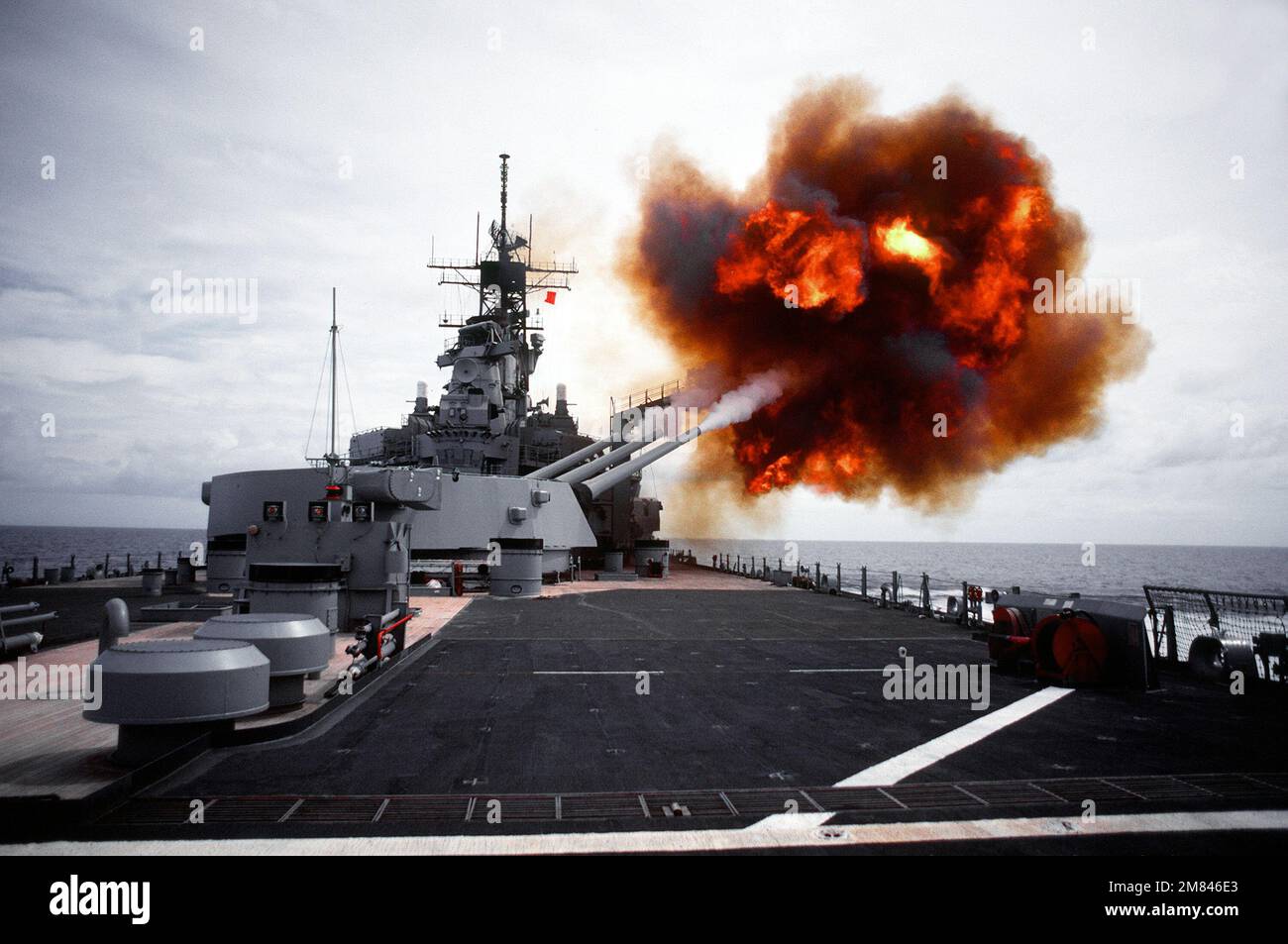 Ein Salvo wird vom Geschützturm Nr. 3 Mark 7 16 Zoll/50 Kaliber an Bord des Schlachtschiff USS IOWA (BB-61) abgefeuert. Der Geschützturm ist so weit vorne wie möglich auf der Steuerbordseite trainiert, mit Waffen, die auf die Ebene der BGM-109-Raketenwerfer für Tomahawk-Raketen gebracht werden. Die Waffen werden abgefeuert, um den Überdruckwiderstand des Abschussgeräts zu bestimmen. Vierte Ansicht in einer Reihe von fünf. Land: Unbekannt Stockfoto