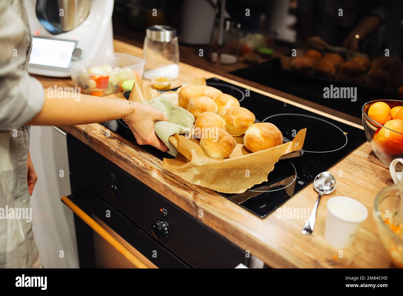Die Hände einer Frau legen ein Tablett mit goldbraunen Kuchen auf die Kochplatte. Backen in der Küche. Heißes, leckeres, frisches Gebäck. Stockfoto