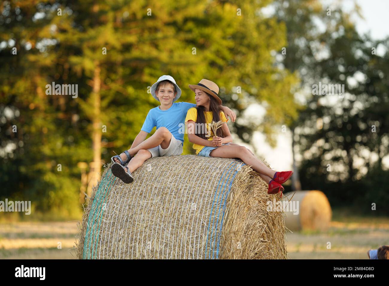 Ein Junge und ein Mädchen im Alter von 10-15 Jahren sitzen auf einem Heuhaufen Stockfoto