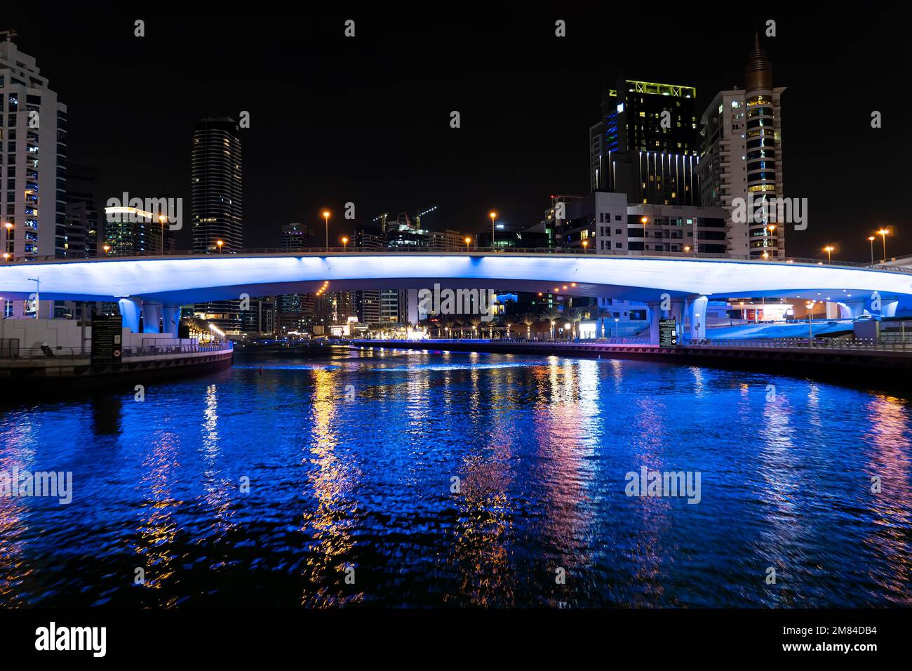 Panoramablick auf die Fußgängerbrücke mit Touristen, die zu zahlreichen Wolkenkratzern mit Hotels und Wohngebäuden an der Küste des Persischen Golfs in Dubai führen Stockfoto