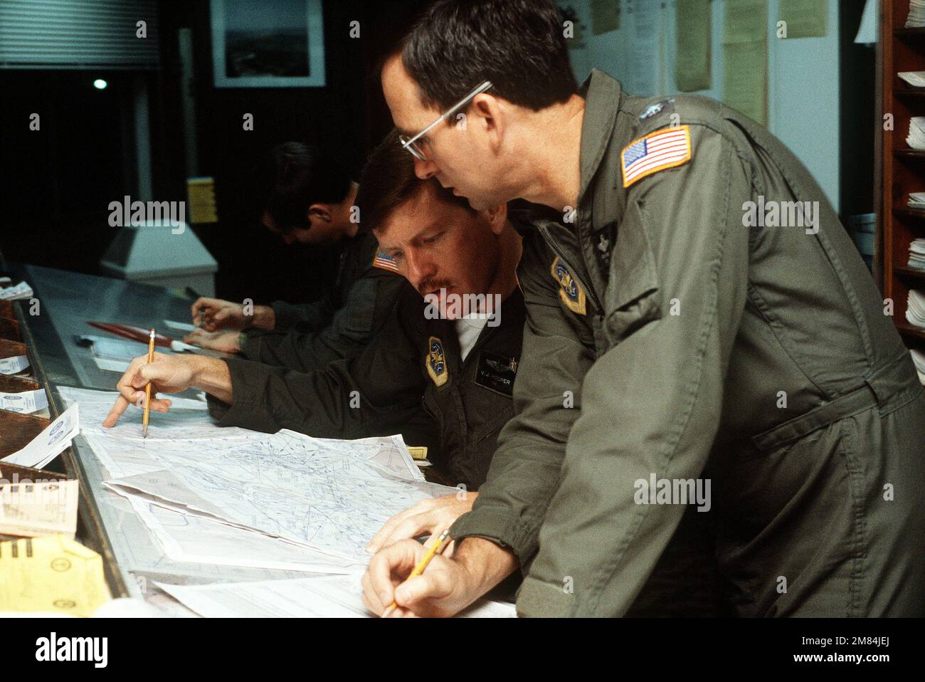 Von rechts nach links, MAJ. Victor Hooper, LT. OBERST. Richard Evans und CAPT. Kenneth Riley vom 68. Militärfluggeschwader, berechnen Sie Fluginformationen, bevor Sie von der Basis abfliegen. Die 68. MAS luftierte die Versorgung und Ausrüstung des Luftstützpunktes. Basis: Yokota Air Base Country: Japan (JPN) Stockfoto