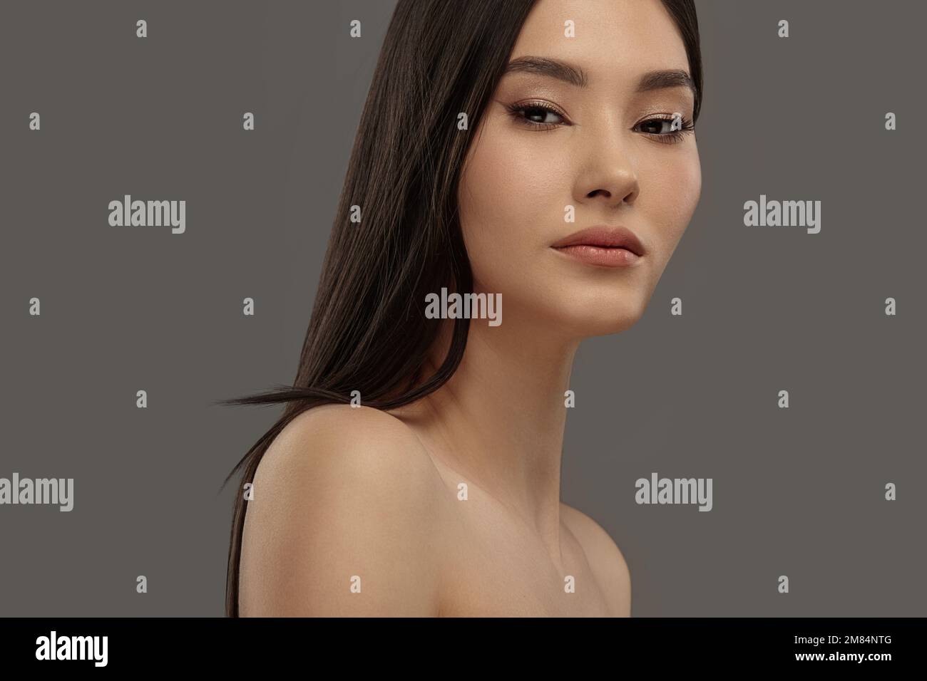Junges, schönes asiatisches Schönheitsmodell auf einem grauen, isolierten Hintergrund. Stockfoto