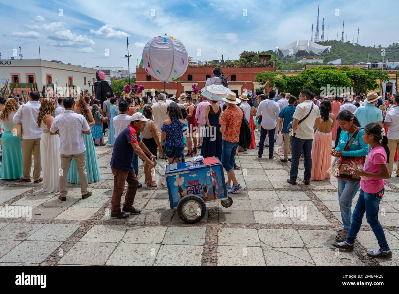 Ein Eisverkäufer geht hinter die Menge bei einer Hochzeitsfeier vor der Kirche Santo Domingo, Oaxaca, Mexiko. Der riesige zeltartige Guel Stockfoto