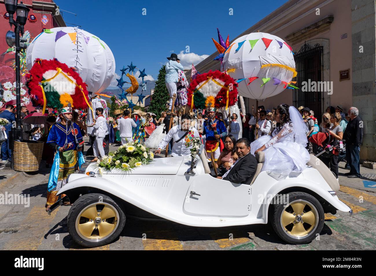 Eine Braut auf dem Rücken eines klassischen MG-Sportwagens auf einer Hochzeitsfeier auf der Straße in Oaxaca, Mexiko. Stockfoto