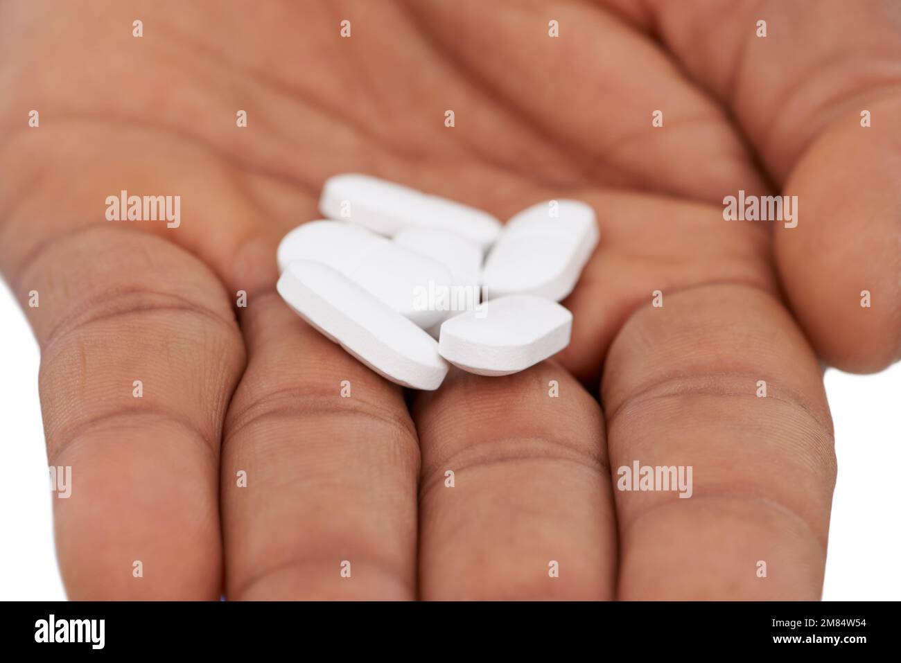 Es wird empfohlen, täglich ein Multi-Vitamin einzunehmen. Nahaufnahme einer männerhand mit einer Dosis weißer Pillen. Stockfoto