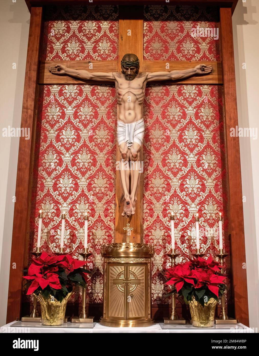 Jesus am Kreuz mit Tabernakel und Poinsettias und Kerzen zu Weihnachten in St. Joseph's Catholic Church in Taylors Falls, Minnesota, USA. Stockfoto